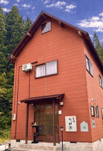 a large orange building with a door and windows at 白山麓の隠れ宿Takeo in Hakusan