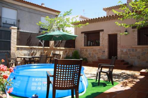 a patio with chairs and an umbrella next to a pool at Casa Rural Parajes del Júcar in Casas de Benítez