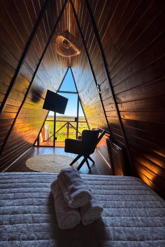 a bedroom with a bed and a chair and a window at Cabanas Farol in Pântano Grande