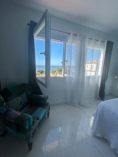 a bedroom with a couch and a window with the ocean at Chalet con 3 habitaciones Luz De Doñana in Mazagón