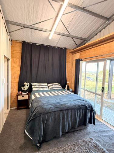 a bedroom with a bed and a large window at Vineyard Cabin in Te Kauwhata