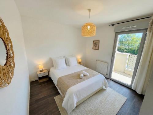 a white bedroom with a bed and a window at Lumen Chartrain - appartement proche centre-ville, balcon et parking in Chartres