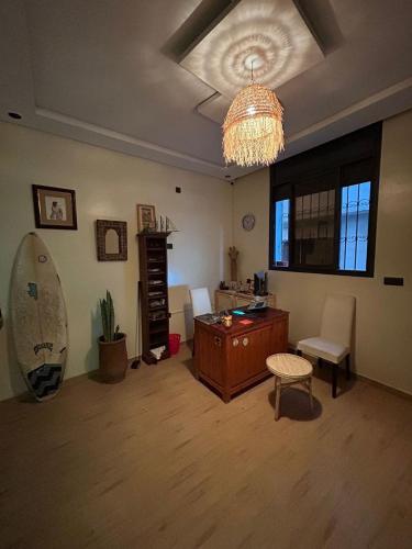 a living room with a desk and a chandelier at Breeze surf lodge in Tamraght Ouzdar