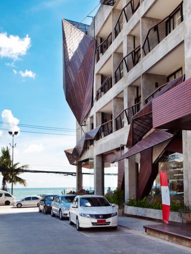 a building with cars parked in a parking lot at The Now Hotel - SHA Extra Plus in Jomtien Beach