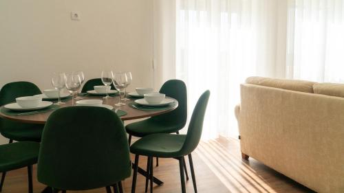 a dining room table with green chairs and a couch at Cantinho Dos Avós - Alojamento Local in Canas de Senhorim