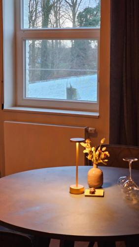 a table with a vase on it with a window at B&B T'Rest - Park ter Rijst in Heikruis