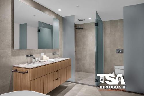 a bathroom with a sink and a mirror and a shower at Black Bear 402 in Thredbo