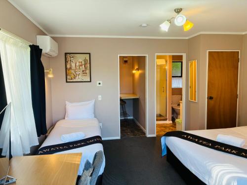 a hotel room with two beds and a table at Awatea Park Motel in Palmerston North