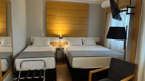 a hotel room with two beds and a chair at Suíte Aeroporto Congonhas Quarto Triplo in São Paulo