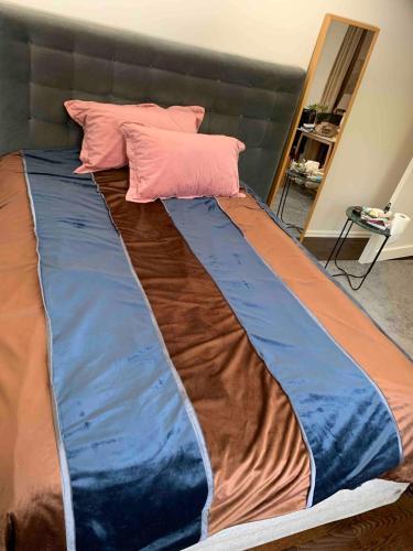 a bed with blue and brown sheets and pink pillows at Raufoss Villa Residence in Raufoss
