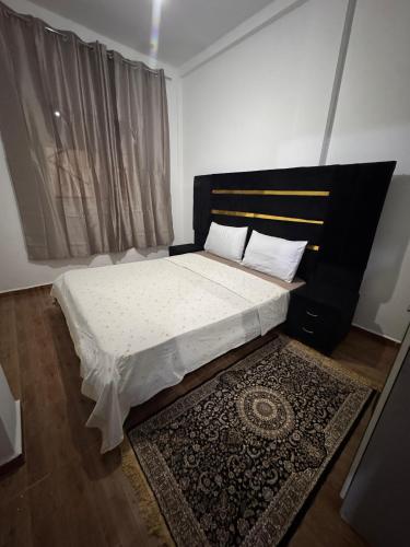 a bedroom with a bed with a black headboard and a rug at Le Nide d'azrou in Azrou