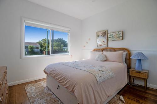 a bedroom with a large bed and a window at Palms on Wunda in Sussex Inlet