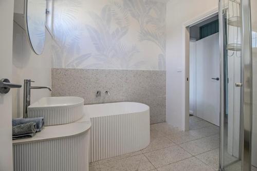 a bathroom with two sinks and a bath tub at Palms on Wunda in Sussex Inlet