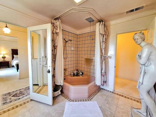 a bathroom with a bath tub and a statue of a man at Fairy Hill Sanctuary in Monte Sereno