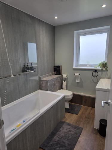 a bathroom with a bath tub and a toilet at Charming three bedroom house in Durham in Brandon
