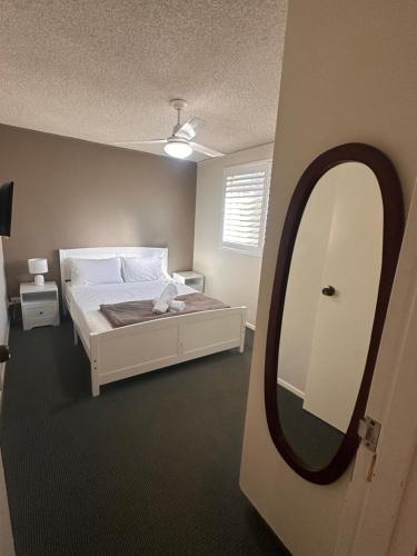 a bedroom with a bed and a large mirror at Beachlander Self-Contained Holiday Apartments in Coffs Harbour
