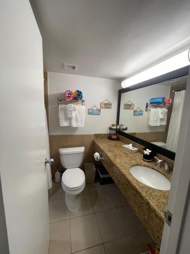 a bathroom with a toilet and a sink and a mirror at Penthouse unit at Palms Waikiki in Honolulu
