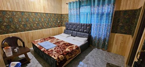 a bedroom with a bed and a curtain and a table at Hotel First Kashmir in Srinagar