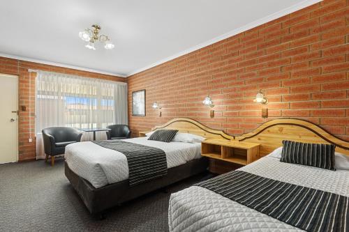 a hotel room with two beds and a brick wall at Edithburgh Seaside Motel in Edithburgh