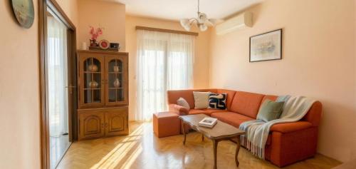 a living room with an orange couch and a table at Apartment Novi II in Kaštela