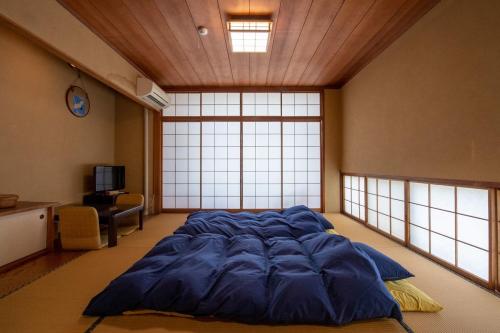 a large blue bed in a room with windows at Ryokan -Suikoen- by Tranova in Yugawara