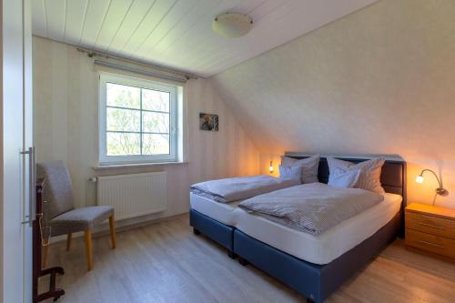 a bedroom with a bed and a window and a chair at Hus-Pellworm-2-Ferienwohnung-Meereswelle in Pellworm