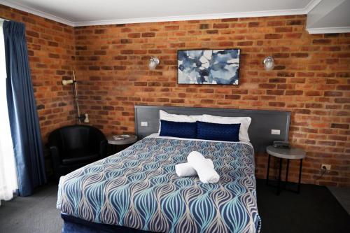 a bedroom with a bed and a brick wall at Paddlewheel Motel in Echuca