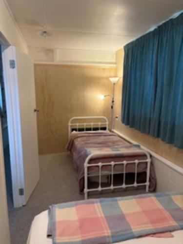 a small room with two beds and a window at Hosts on the Coast Ocean Corner in Whangamata