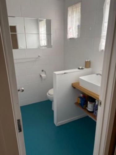 a white bathroom with a sink and a toilet at Hosts on the Coast Ocean Corner in Whangamata