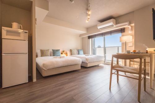 a hotel room with two beds and a table and a kitchen at ESLEAD HOTEL Namba East in Osaka