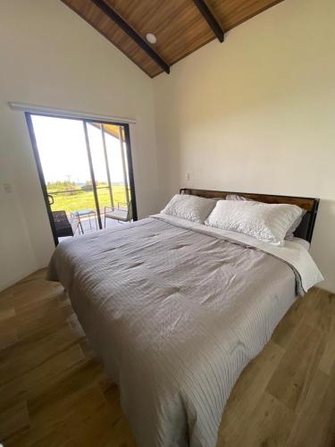 a bedroom with a large bed with a large window at Cabaña Vistas de Lujo in Fraijanes
