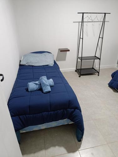 a bed with a blue comforter in a room at Casa Ruta 3 Río Gallegos in Río Gallegos