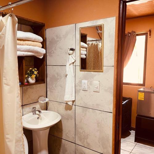 a bathroom with a sink and a shower with towels at Macaws Villa in Ciudad Cortés