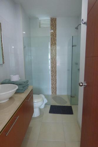 a bathroom with a toilet and a glass shower at Costa Azul Suites 403 in Santa Marta
