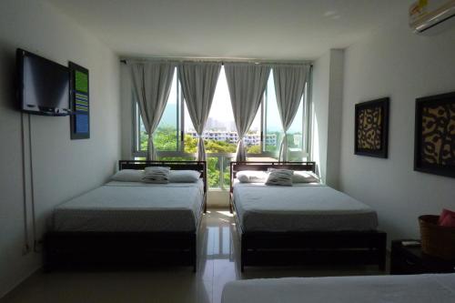 a bedroom with two beds and a large window at Costa Azul Suites 403 in Santa Marta