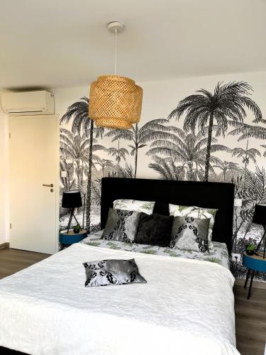 a bedroom with a white bed with palm trees on the wall at Villa l'Immortelle in Zonza