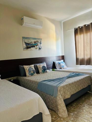 a bedroom with two beds and a window at VOER - BR Flat Hospedaria in Sete Lagoas