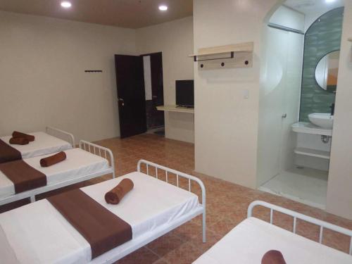 a room with two beds and a bathroom with a sink at Pension Bacolod in Bacolod