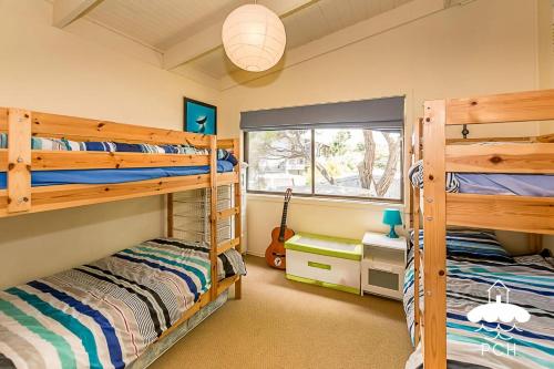 a bedroom with two bunk beds and a guitar at Dune Cottage Stay 3 Pay 2 Winter Special in Sandy Point