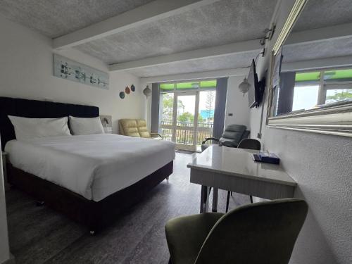 a hotel room with a bed and a desk and chairs at Le George Motel in Port Macquarie