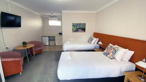 a hotel room with two beds and a table at Higgins Lane Motel in Margaret River Town