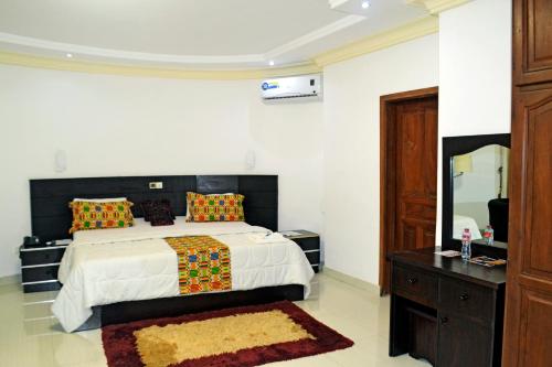 a bedroom with a bed and a dresser and a mirror at Beach Sand Hotel & Resort, Cotonou in Cotonou
