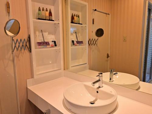 a white bathroom with a sink and a mirror at ホテルラフィネ in Toyonaka