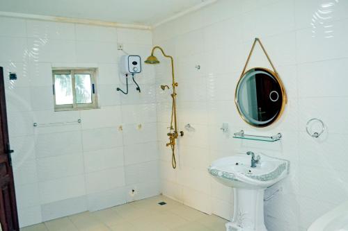 a white bathroom with a sink and a mirror at Beach Sand Hotel & Resort, Cotonou in Cotonou