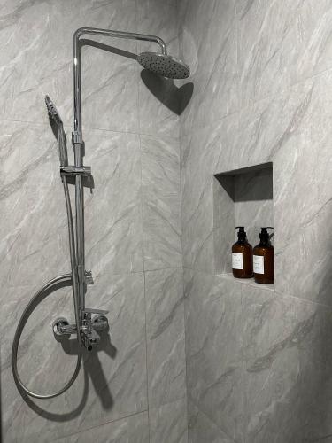 a shower in a bathroom with two bottles of soap at Serenity Homestay Penuin Batam in Batam Center