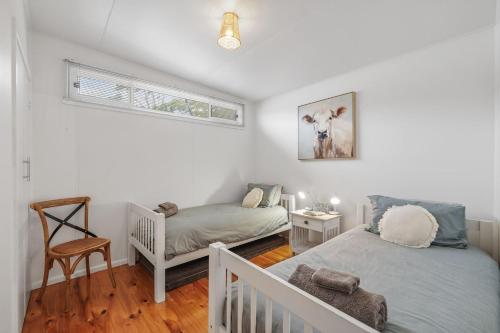 a bedroom with two twin beds and a chair at The Bach at Ventnor in Ventnor