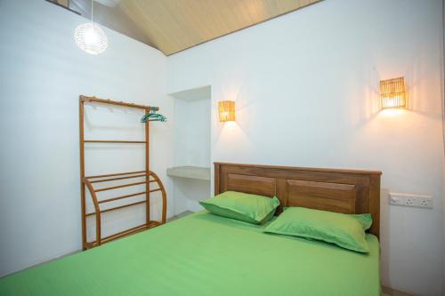 a bedroom with a green bed with two green pillows at Nasha Lanka House in Koggala