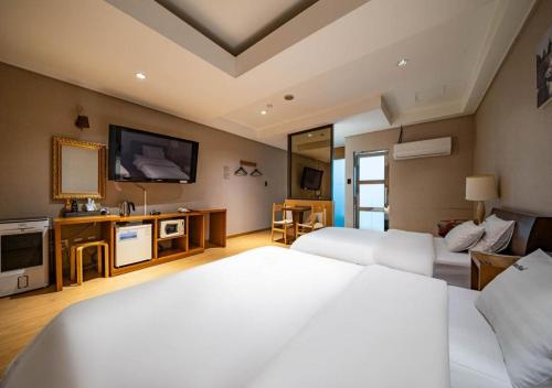 a hotel room with two beds and a flat screen tv at Nabeeya Hotel in Siheung