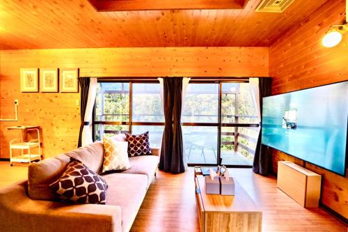 a living room with a couch and a large window at 貸切温泉付き宿 風蒼 Huua in Kirishima
