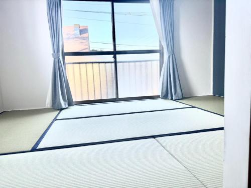 an empty room with a large window with curtains at 貸切温泉付き宿 風蒼 Huua in Kirishima